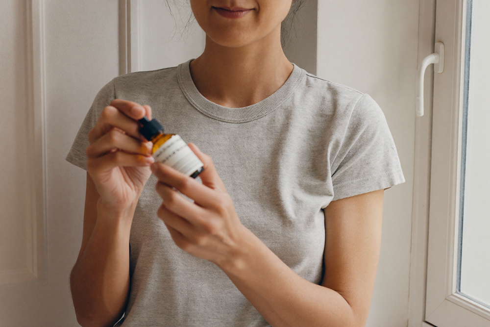 A woman turning a dropper bottle over to read the back of it